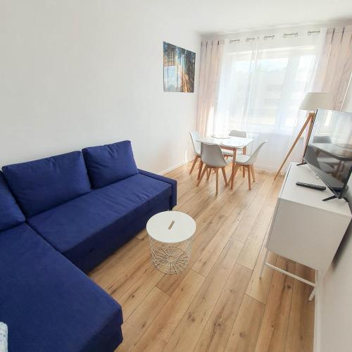 een woonkamer met een blauwe bank en een tafel bij Apartament Kurka in Hajnówka