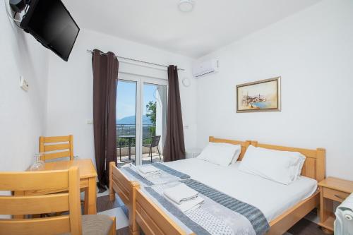 a bedroom with a bed and a desk and a window at Guest house Vila Vedesa in Kotor