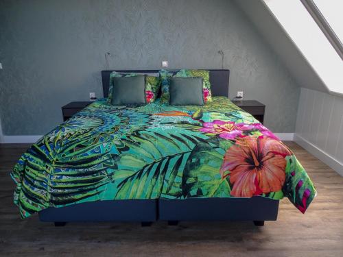 1 dormitorio con 1 cama con un edredón colorido en Bed & Breakfast De Leekerhoek, en Oosterleek