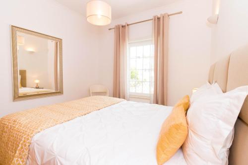 une chambre avec un lit avec un miroir et une fenêtre dans l'établissement ALzira By Rossio, à Albufeira