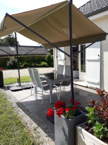 - un parasol sur une terrasse avec des chaises et des fleurs dans l'établissement L'ABRI des ÂMES, à Gerponville
