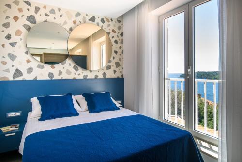 a bedroom with a blue bed and a mirror at Villa Leoni in Dubrovnik