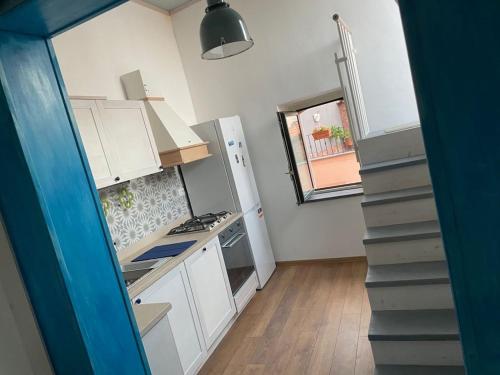 a small kitchen with white cabinets and a staircase at donna serena Aci Castello in Aci Castello