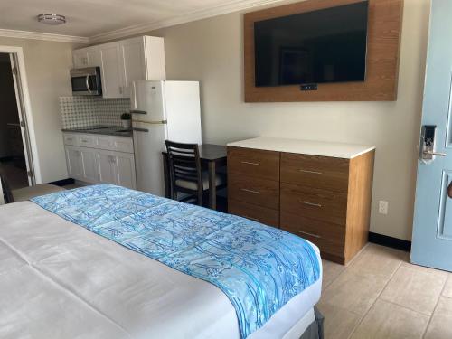 a bedroom with a bed and a kitchen with a refrigerator at Coastal Sands Inn in Wildwood
