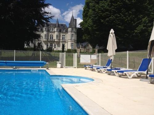 une piscine avec des chaises et une maison en arrière-plan dans l'établissement Château de Vallagon, à Bourré