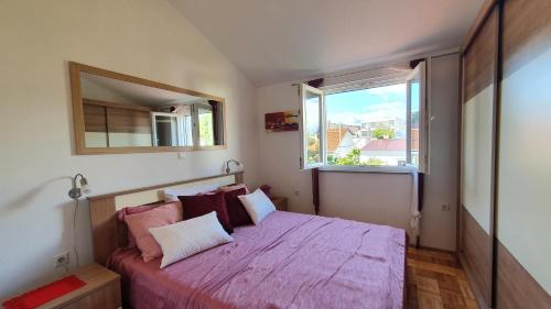 ein Schlafzimmer mit einem Bett mit einer rosa Decke und einem Fenster in der Unterkunft Apartmani Villa Lilliana in Tribunj