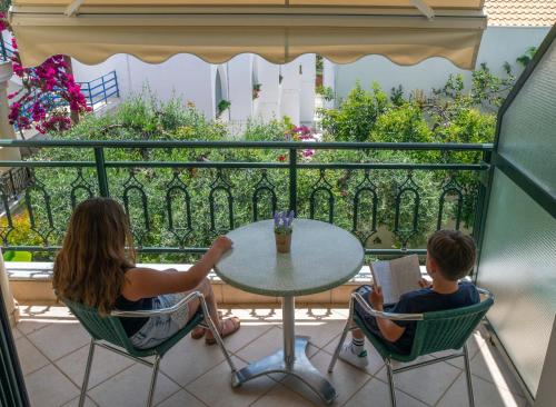 a woman and a boy sitting at a table on a balcony at Hotel Loukas Vrachos in Paralia Vrachou