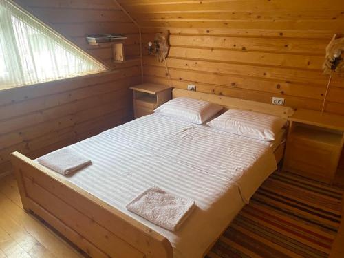1 dormitorio con 1 cama en una habitación de madera en Sadyba Sukhar, en Kolochava