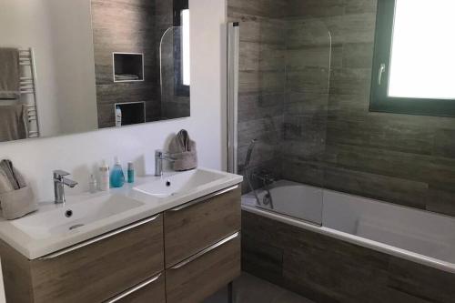 La salle de bains est pourvue d'un lavabo, d'une baignoire et d'une douche. dans l'établissement Villa MERYA piscine & plage, au Grau-dʼAgde