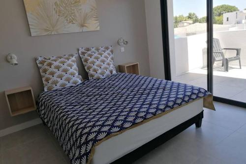 - un lit avec une couette bleue et blanche dans une chambre dans l'établissement Villa MERYA piscine & plage, au Grau-dʼAgde