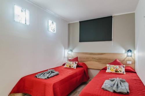 a bedroom with two beds with red sheets and a flat screen tv at Luxury apt 1 MINUTE from the Beach of the Dunes in Playa del Ingles