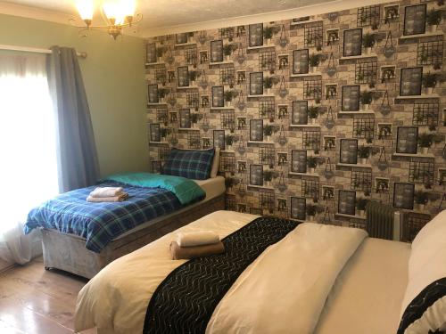 two beds in a room with a wall with pictures at Bright Apartments in Peterborough