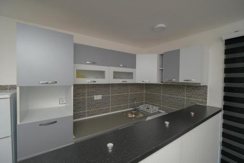 a kitchen with white cabinets and a black counter top at Vila melek 4 bedrooms in Sarajevo