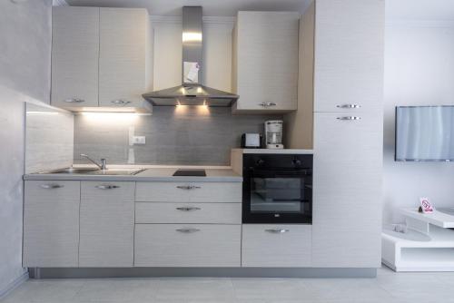 cocina con armarios blancos, fregadero y microondas en Apartment Tonka, en Cavtat