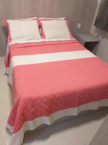 a large bed with a red and white blanket at Flat Paraiso dos Coqueiros in Guarajuba