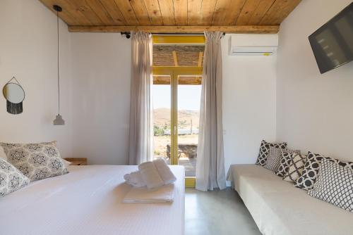 a bedroom with a white bed and a couch at Themonies Suites and Apartments in Kithnos