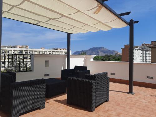 a patio with chairs and a white umbrella on a roof at Triscele house in Palermo