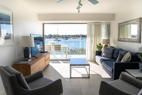 sala de estar con sofá y vistas al agua en Aqua Linea, en Noosa Heads