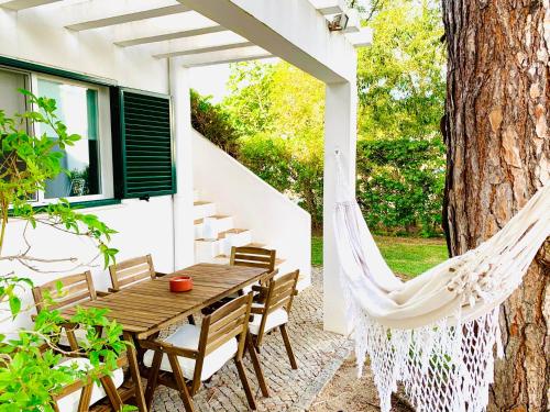 a hammock on a patio with a table and chairs at GOLF & BEACH VILLA in Vale do Lobo