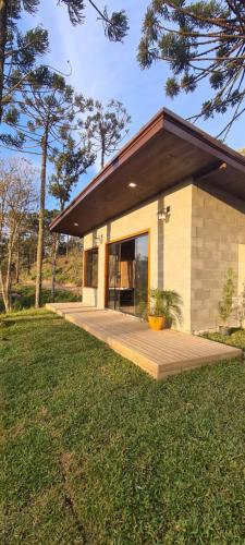 a small house with a wooden deck in the grass at Sunset Serrano Chalés in Urubici