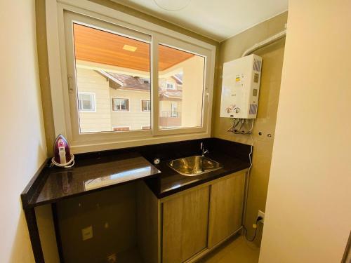 a small kitchen with a sink and a window at MRG - Completo 2 Suítes a 600m Rua Coberta in Gramado