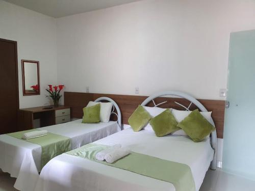 two beds with green pillows in a room at Aconchego Sertanejo in Caetité