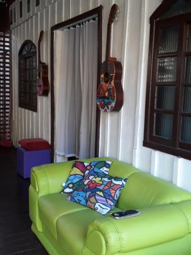 een groene bank in een woonkamer met een gitaar bij RECANTO DO SOL "Aluguel de quartos - Hospedagem Simples" in Ilha do Mel