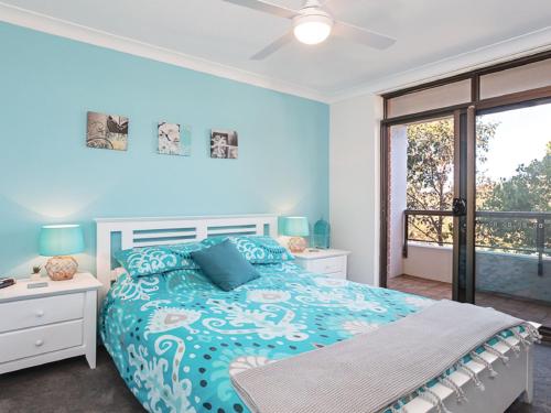 a blue bedroom with a bed and a balcony at The Commodore, 23,9-11 Donald Street - Delightful unit with gorgeous water views, air con and wi-fi in Nelson Bay