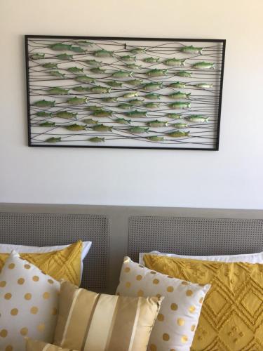a picture hanging above a bed with yellow pillows at Ocean Breeze Apartment Portland in Portland