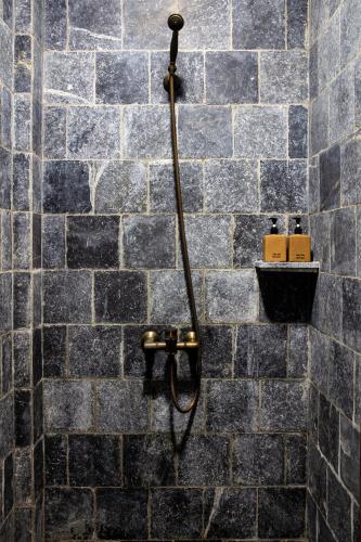 a shower in a bathroom with a stone wall at Làng Nương Yên Tử (Yên Tử Village) in Uông Bí