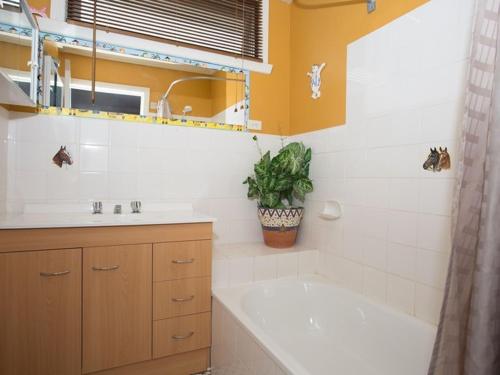 a bathroom with a tub and a sink and a shower at Banksia Seven in Merimbula