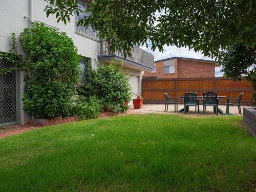 a yard with chairs and a table in front of a house at Banksia Seven in Merimbula