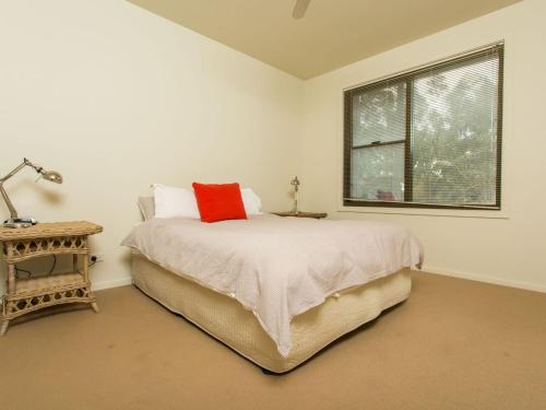 ein Schlafzimmer mit einem Bett mit einem roten Kissen darauf in der Unterkunft Rolling Waves No 2 in Merimbula