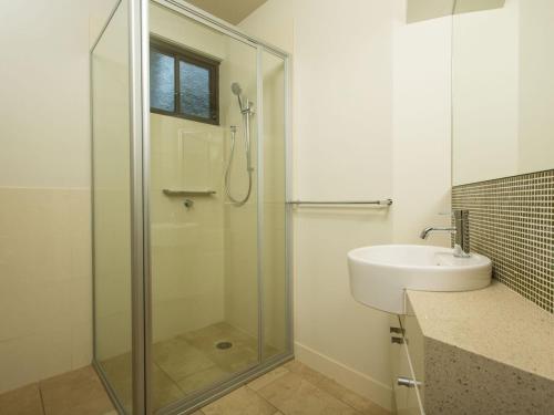 ein Bad mit einer Glasdusche und einem Waschbecken in der Unterkunft Rolling Waves No 2 in Merimbula