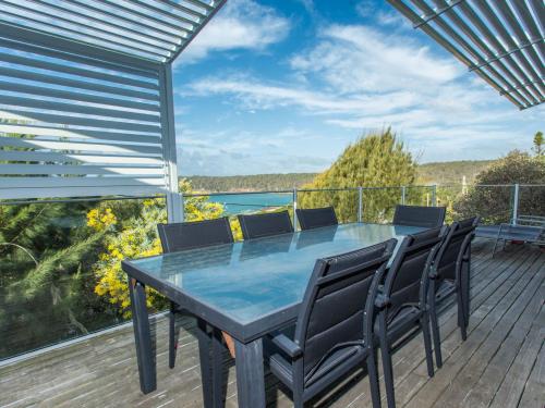 a dining table on a deck with a view of the water at Seascape in Pambula Beach