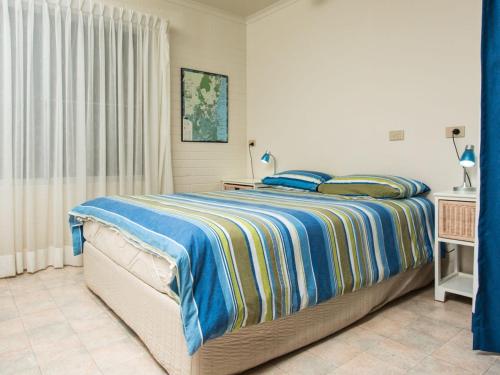 a bedroom with a bed with a blue and yellow blanket at Seascape in Pambula Beach