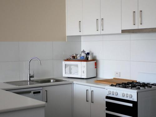a white kitchen with a sink and a microwave at Parkview Motor Inn and Apartments in Wangaratta