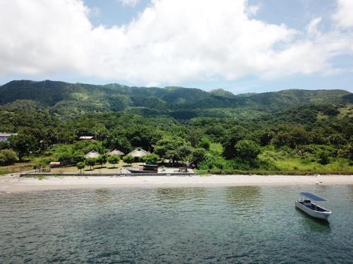 un bateau dans l'eau à côté d'une plage dans l'établissement Atauro Dive Resort, à Beloi