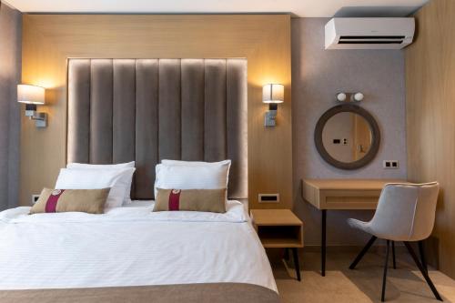 a bedroom with a bed and a desk and a mirror at City Park Inn in Plovdiv