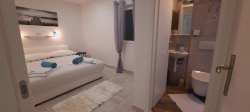 科米扎Apartments SUHO Komiza的一间带床和浴室的白色卧室