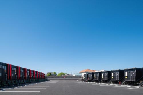 una fila di vagoni ferroviari parcheggiati in un parcheggio di HOTEL R9 The Yard Koga a Koga