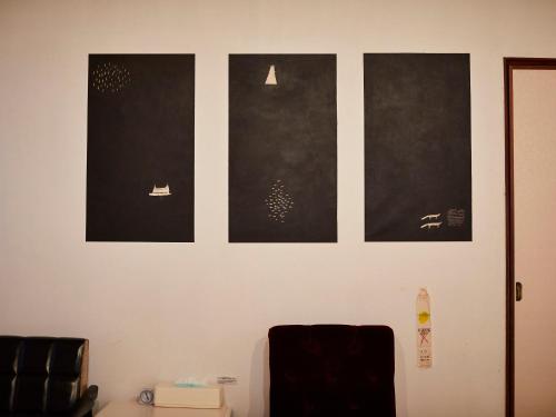 Una pared con cuatro cuadros negros. en Kikusui Ryokan en Tamano