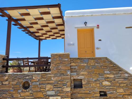 a house with a stone wall and a yellow door at Aigaio Studios tinos in Tinos Town