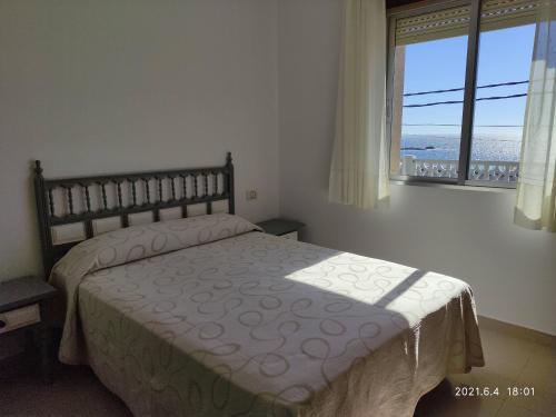 a bedroom with a bed with a view of the ocean at A Casiña do Miramar in A Lanzada