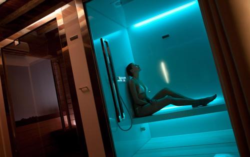 a woman is sitting in a glass shower stall at Il Tesoro Living Resort in Rodigo