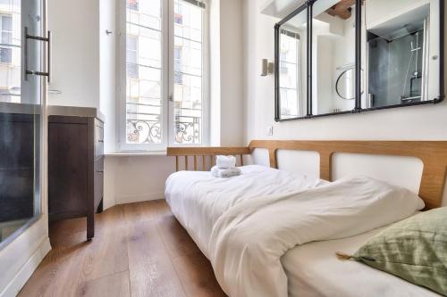 une chambre avec un lit et un miroir au mur dans l'établissement Cute and New Studio Duplex in the Heart of Paris, à Paris
