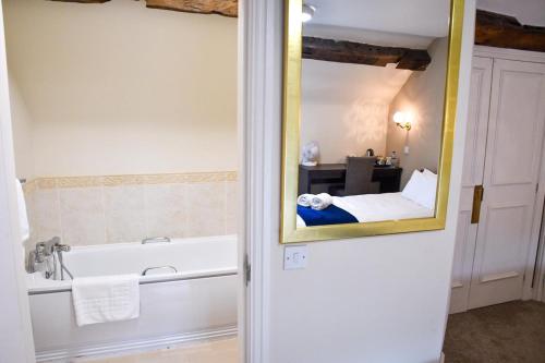 a bathroom with a mirror and a bath tub at Whiston Hall in Whiston