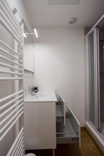 une salle de bain blanche avec un lavabo et une fenêtre dans l'établissement Studios du Marché au Bois, à Périgueux