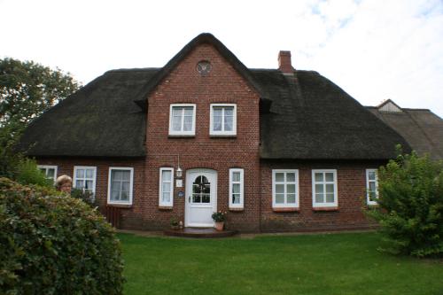 ein großes rotes Backsteinhaus mit einem Schiebedach in der Unterkunft Ferienwohnungen im Hotel garni zur Post in Utersum