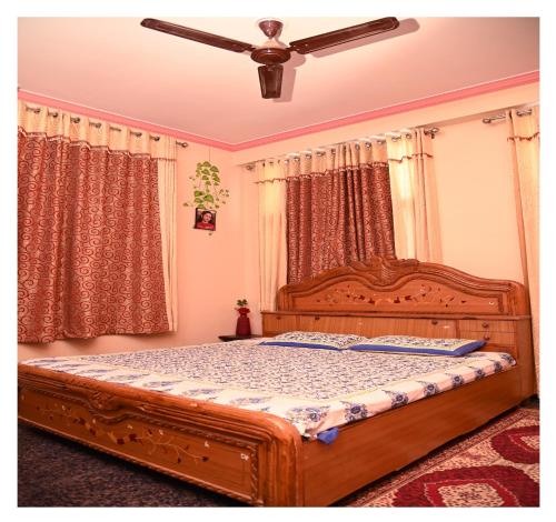 a bedroom with a wooden bed with a ceiling fan at SOHANAs Homestays- 2 BHK Luxury Apartment near Jaipur International Airport in Jaipur